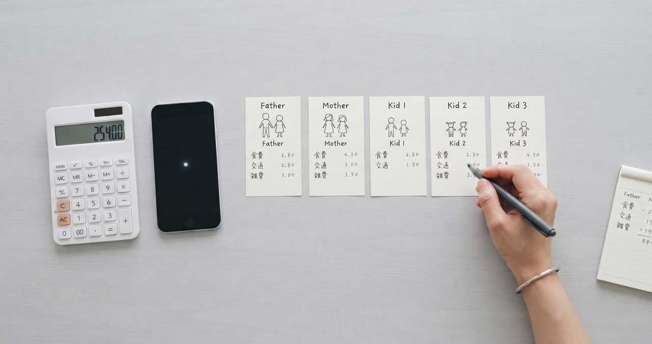 電卓とスマートフォンを並べて、家族の契約プランを比較しながら計算している手元