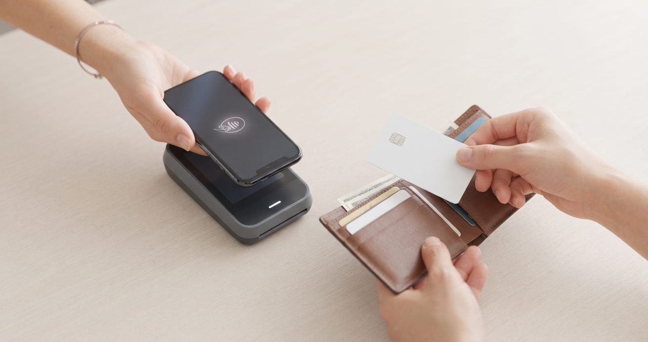 スマートフォンを決済端末にタッチする手元と、もう片方の手でICカードを取り出そうとしている様子