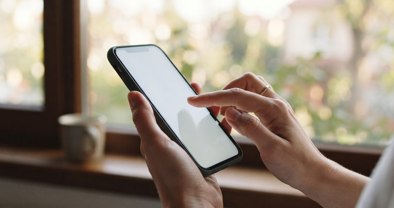 スマートフォンの画面を指でタップしようとしている手元のクローズアップ、MNP予約番号を取得する操作をイメージした写真